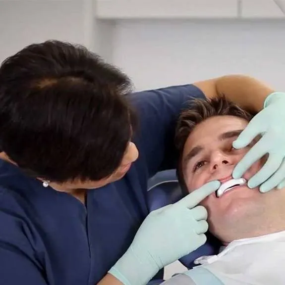 A dentist fitting an oral appliance for a patient
