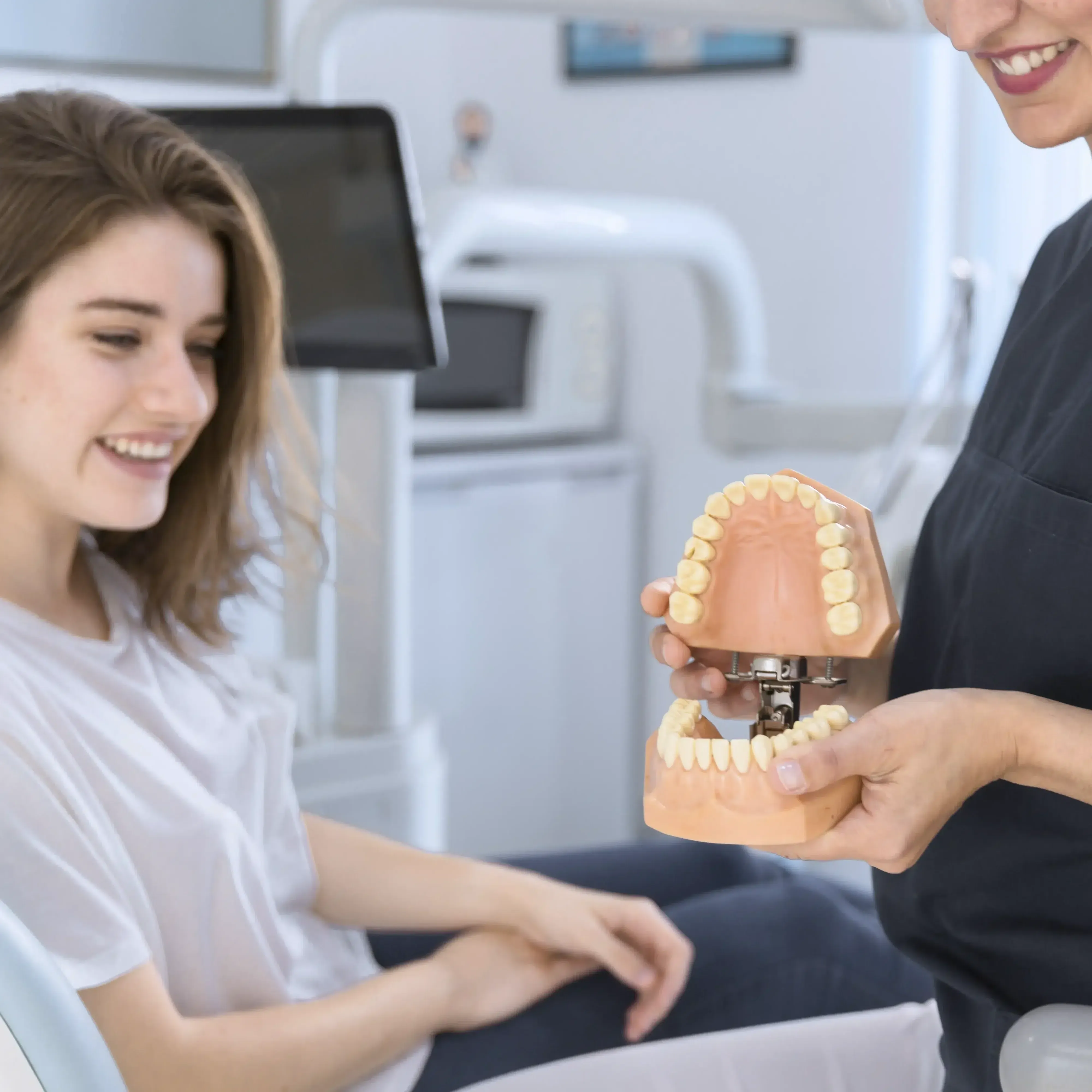 A dentist showing a smiling patient a model of teeth